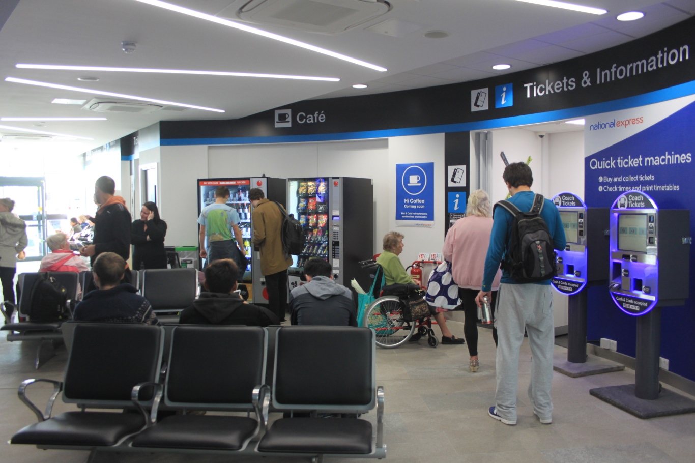 A coach station ticket office with machines and waiting passengers