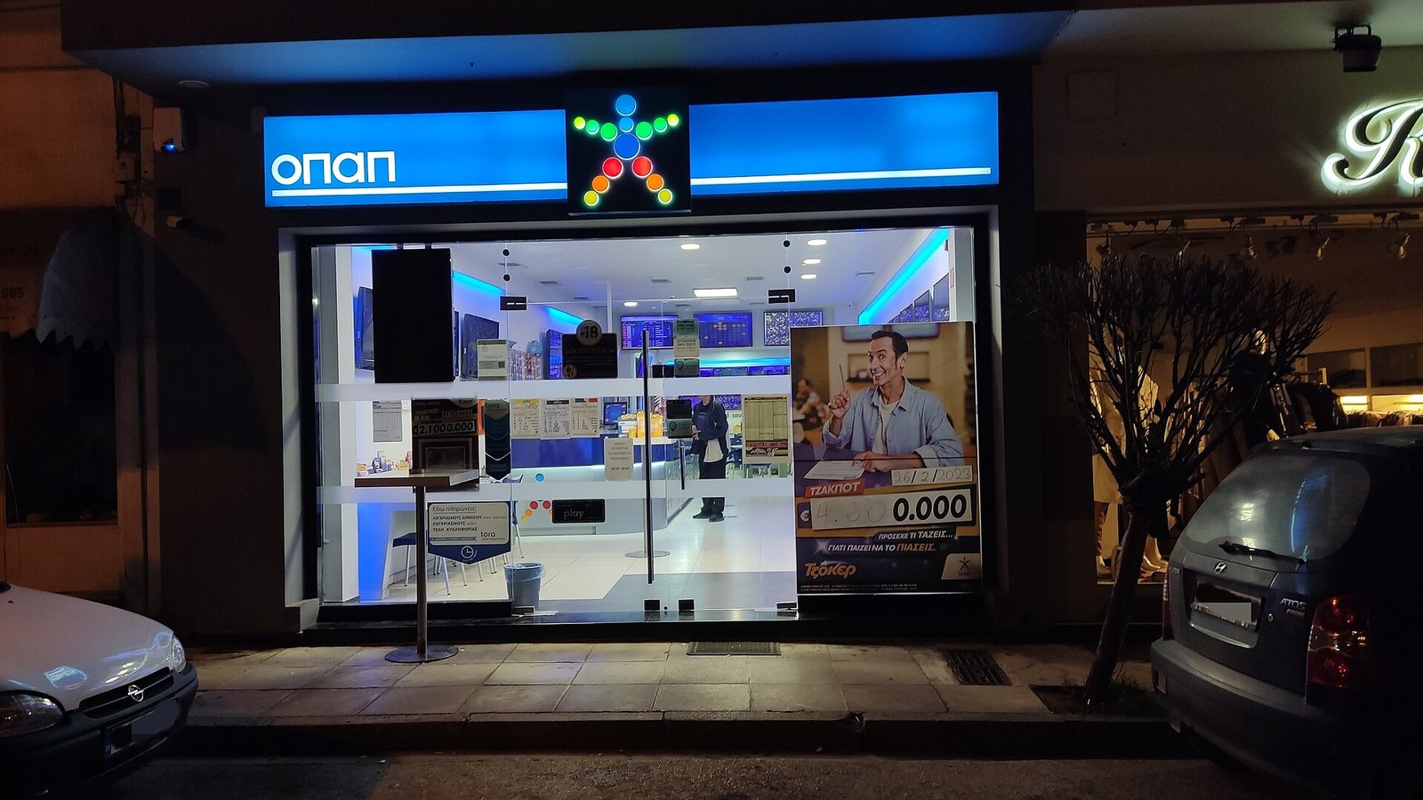 A lit betting shop front at night with a screen in the window
