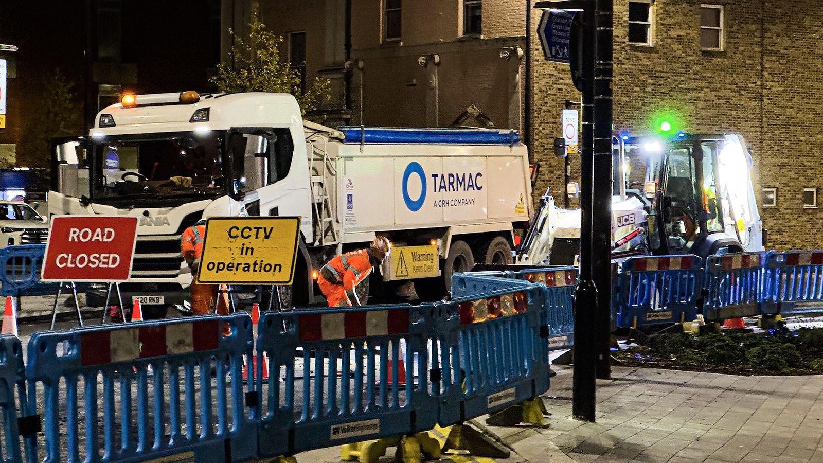 Night road works with ROAD CLOSED signs, barriers and a tipper lorry