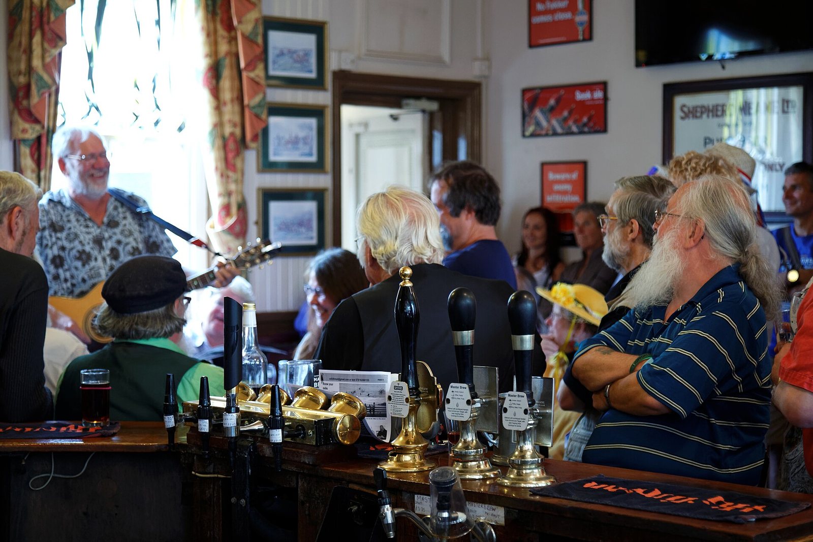 A busy pub bar with people and a band playing