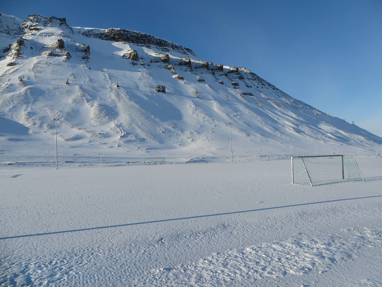 A frozen football pitch with goalposts, snow on the ground
