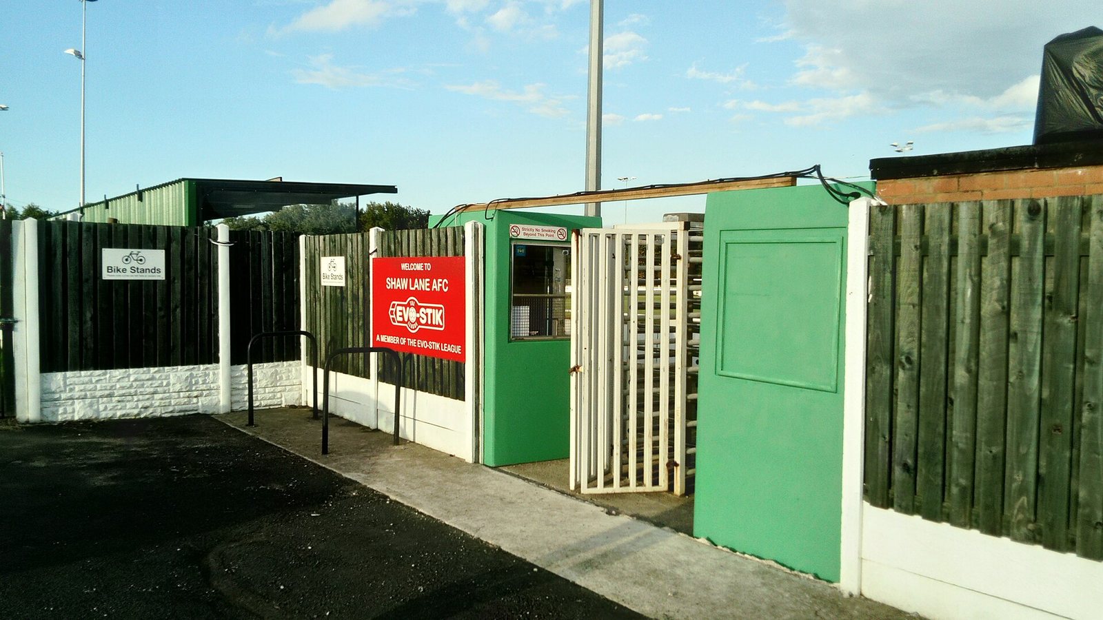 Green turnstiles at the entrance to a small football ground