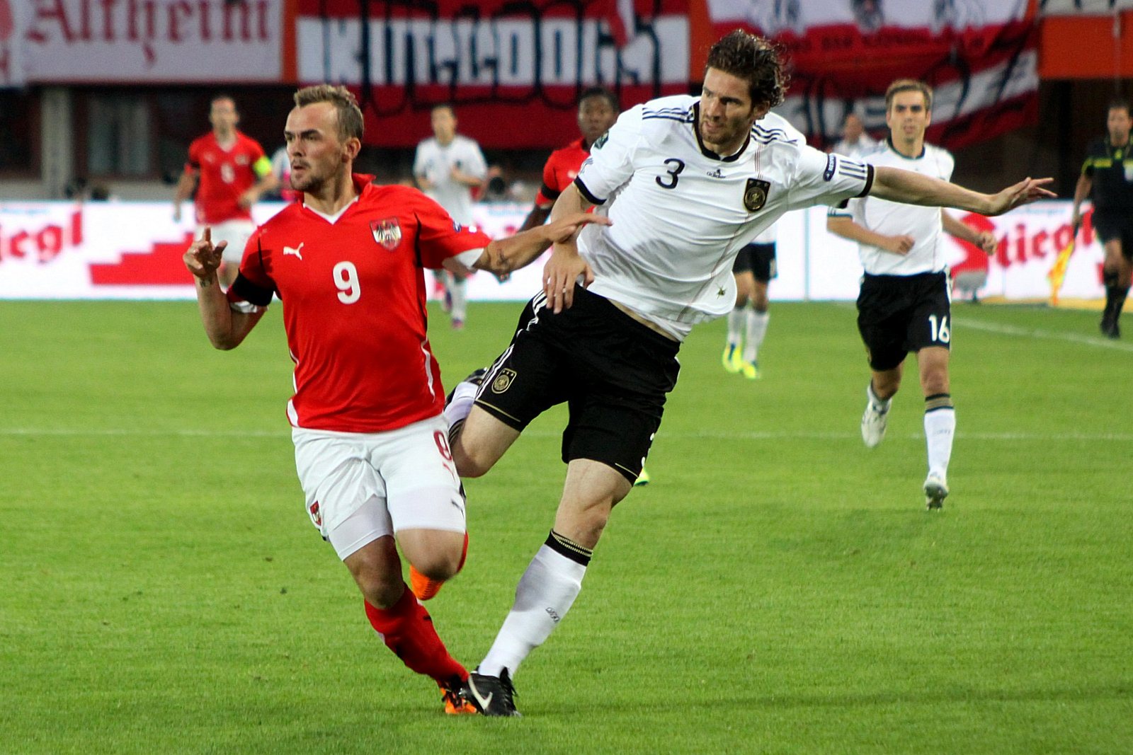 Two footballers competing for the ball in an international match