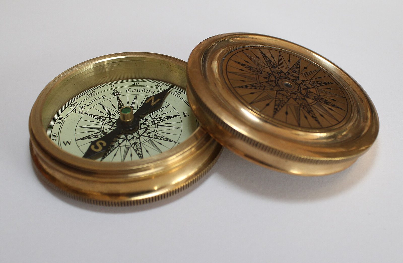 An open brass pocket compass on a white surface
