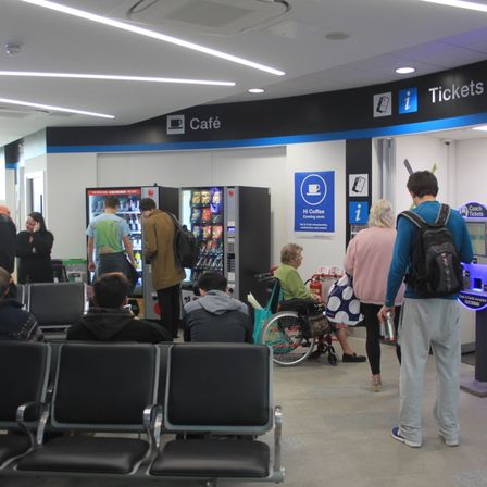 A coach station ticket office with machines and waiting passengers