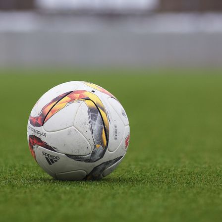A match ball resting on a grass pitch