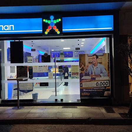 A lit betting shop front at night with a screen in the window