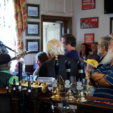 A busy pub bar with people and a band playing