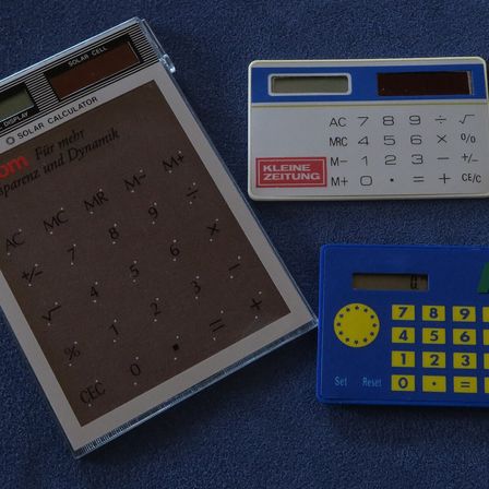 Two pocket calculators on a dark surface