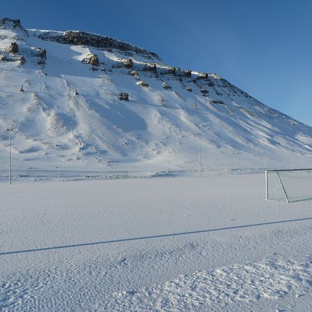 A frozen football pitch with goalposts, snow on the ground