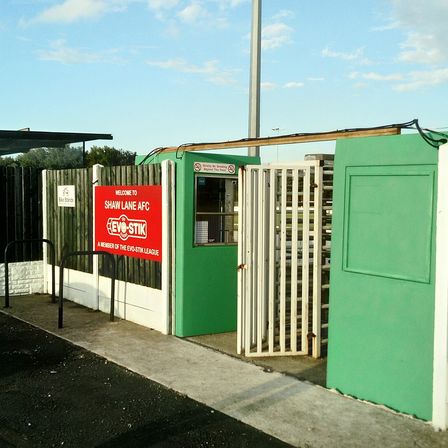 Green turnstiles at the entrance to a small football ground