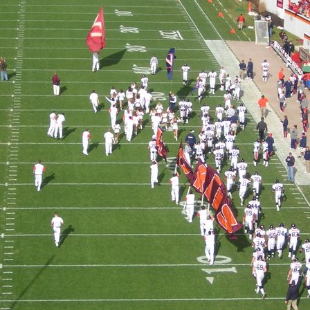 A marching band and cheerleaders on an American football field before kick-off