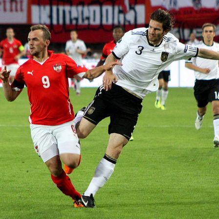Two footballers competing for the ball in an international match